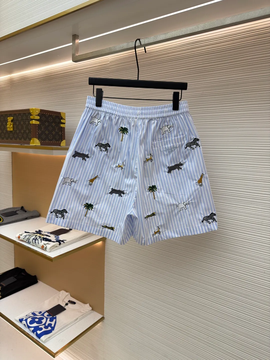 LOUIS VUITTON Animal and plant nostalgic style embroidered striped shorts ●Original version: purchased and developed by 14616 ●Item number: 1682542-A75 ●Fabric: cotton fabric ●Technology: embroidery production ●Color: blue ●Version: fitted version ●Weight: about 205 grams ●Size: S-M-L-XL ●Description: Made of high-count pure cotton poplin fabric. After pre-washing process, it feels smooth and breathable. It has both drape and stiffness, and is not easy to wrinkle and deform. The blue and white vertical stripes on the body are woven with yarn-dyed technology, and the texture is clear and does not fade. The animal and coconut tree patterns are presented with sophisticated embroidery technology. The embroidery threads are full of color and the stitches are dense. The patterns are three-dimensional and vivid, forming a rich visual hierarchy with the stripe base. The shirt has a Cuban collar style, with smooth necklines, custom mother-of-pearl buttons at the placket, and a warm texture. The overall shape is loose, the shoulder joints are straight and fine, the cuffs are cuffed with exquisite craftsmanship, custom accessories and three logos are complete, and the details are full of luxury craftsmanship. It is suitable for casual vacations and daily outings, etc. The overall wiring is straight and delicate, the fabric is comfortable and soft, and the color is consistent without color difference. It can be matched with the same style to create a fashionable look and control various occasions. Customized accessories, complete with three standards, same style for men and women!